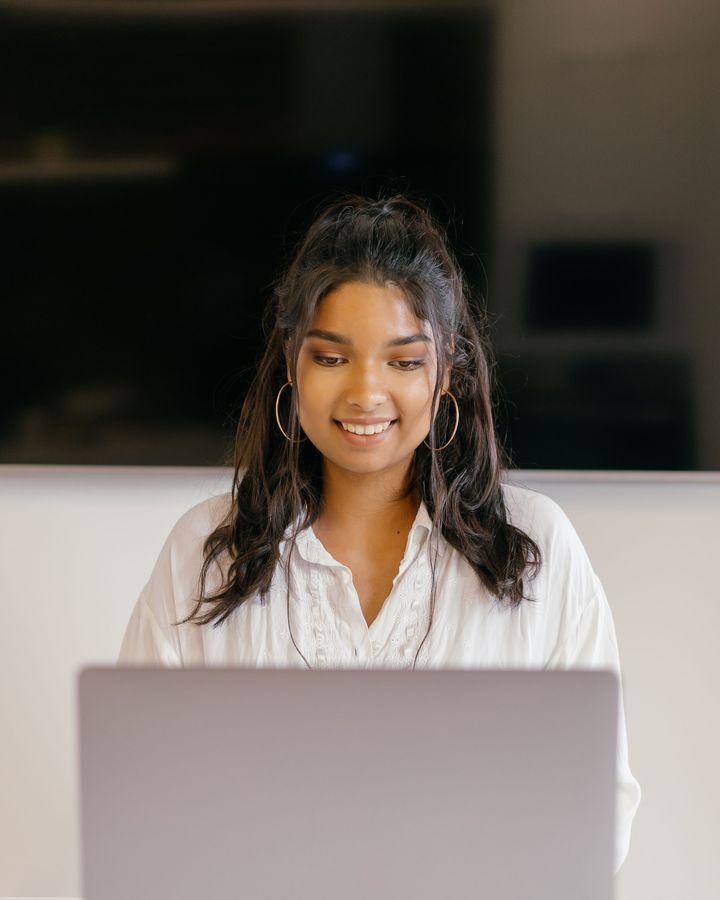 A student smiling over her laptop at a desk