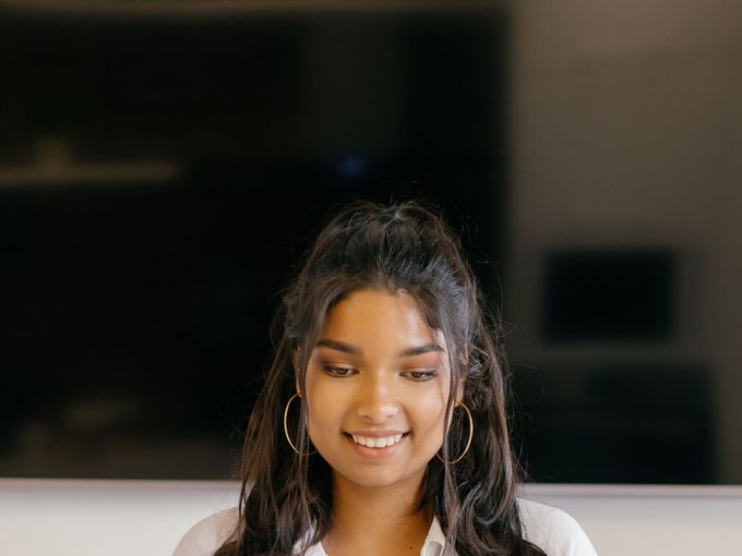 A student smiling over her laptop at a desk