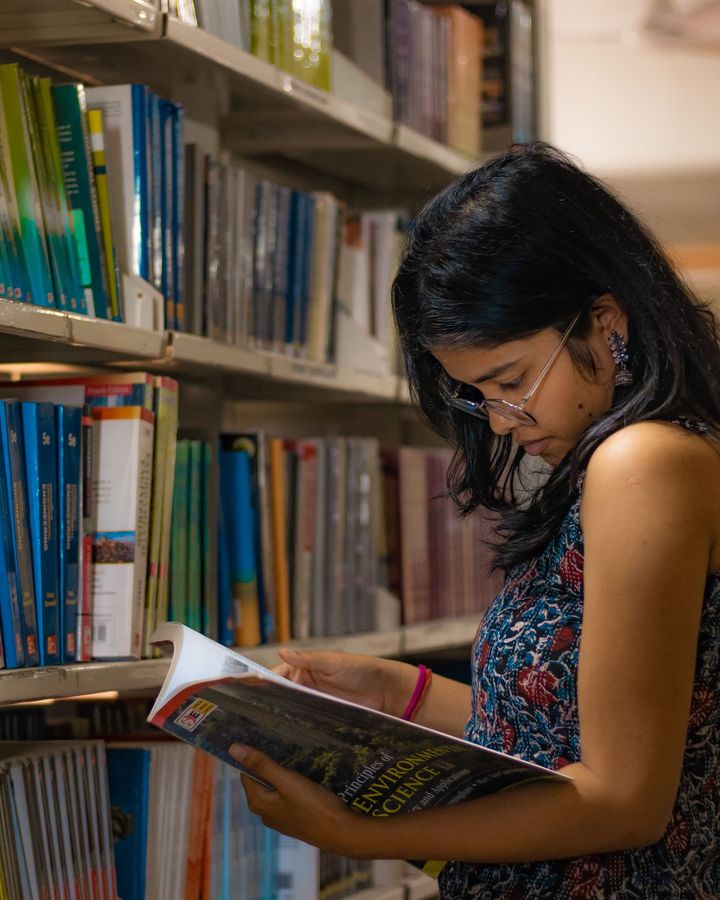 A student reading between library shelves