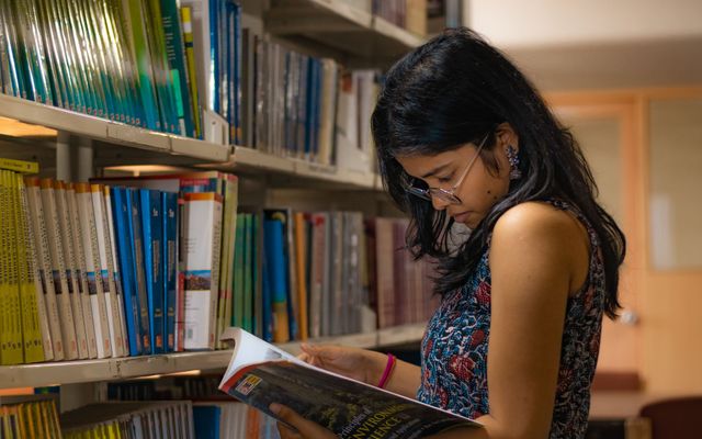A student reading between library shelves