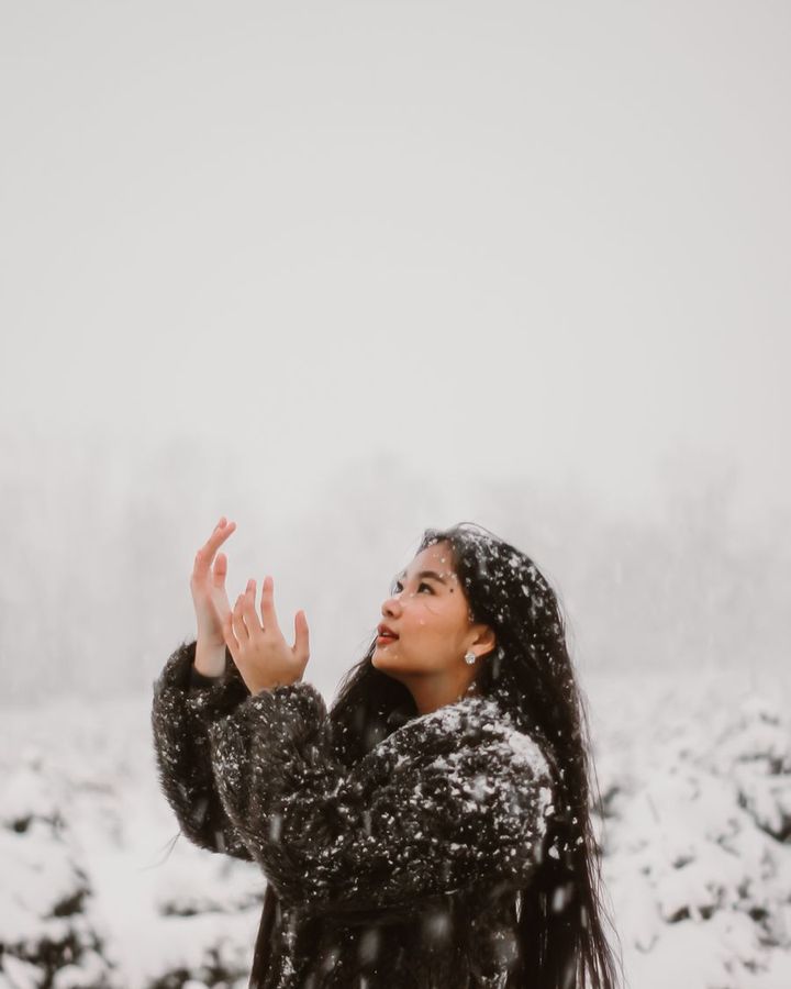 A student looking up at falling snow