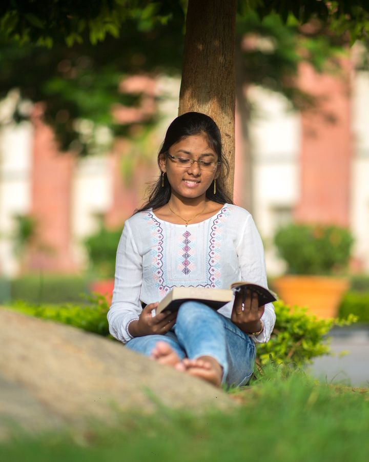 A student reading on the lawn of a brick university building