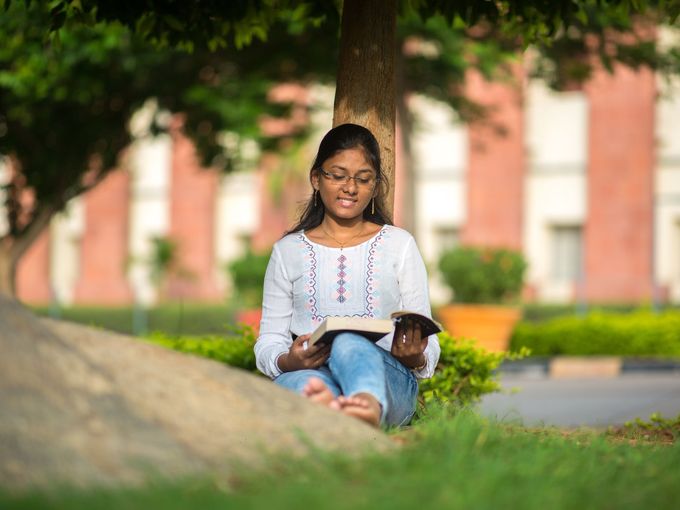 A student reading on the lawn of a brick university building