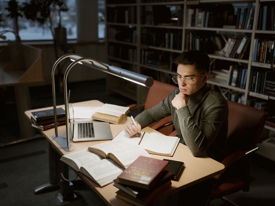A student reading through papers at his desk late at night