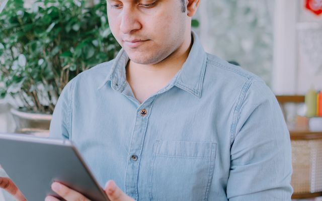 A student reading on his phone at a cafe table