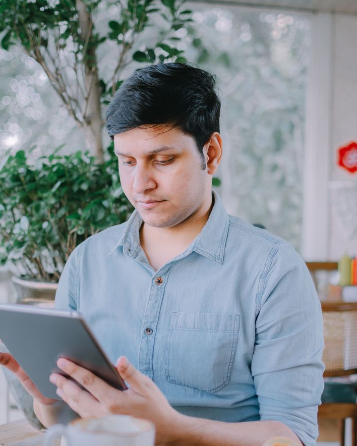 A student reading on his phone at a cafe table