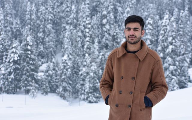 A student in a brown coat in a snowy forest