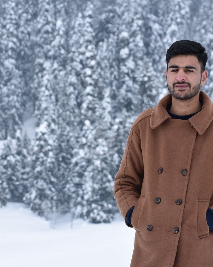 A student in a brown coat in a snowy forest