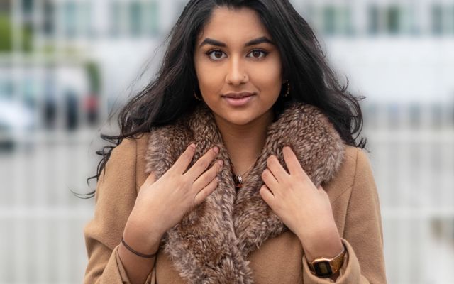A smiling student in a winter coat and scarf
