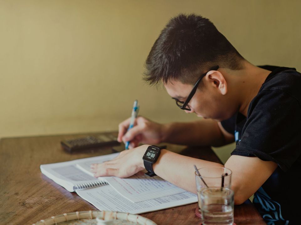 A student writing in a notebook at his desk