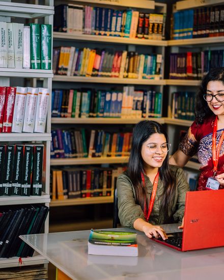 Two students working on a laptop in a library