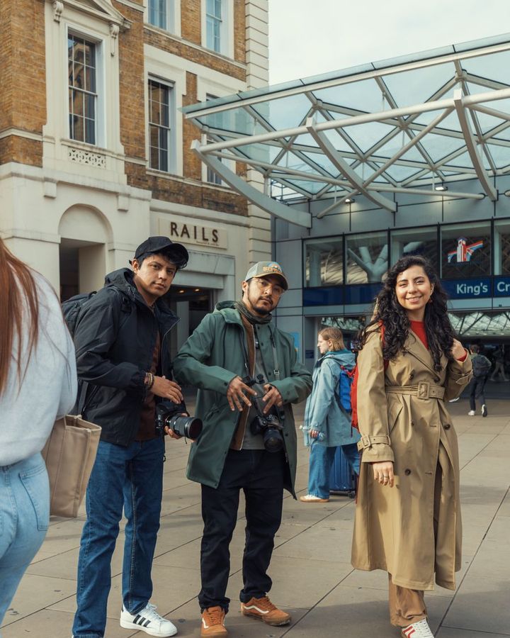 Three students with their bags outside a London railway station