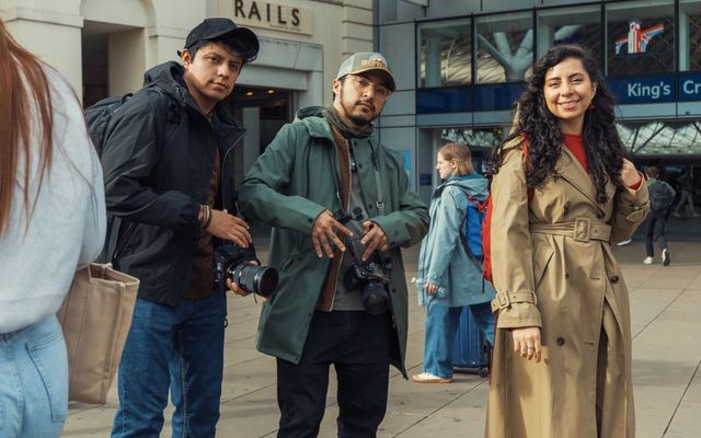 Three students with their bags outside a London railway station