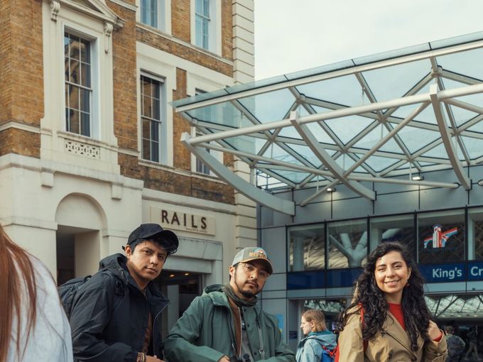 Three students with their bags outside a London railway station