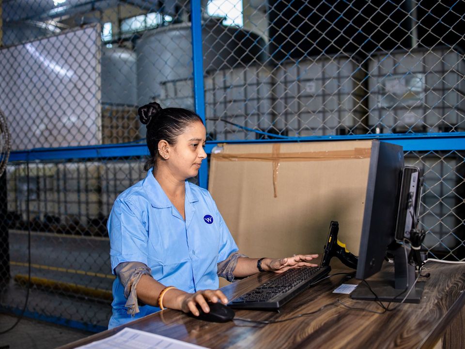 A technician working at her computer on a factory floor