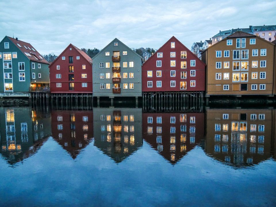 Colourful wooden warehouses reflected in the river in Trondheim