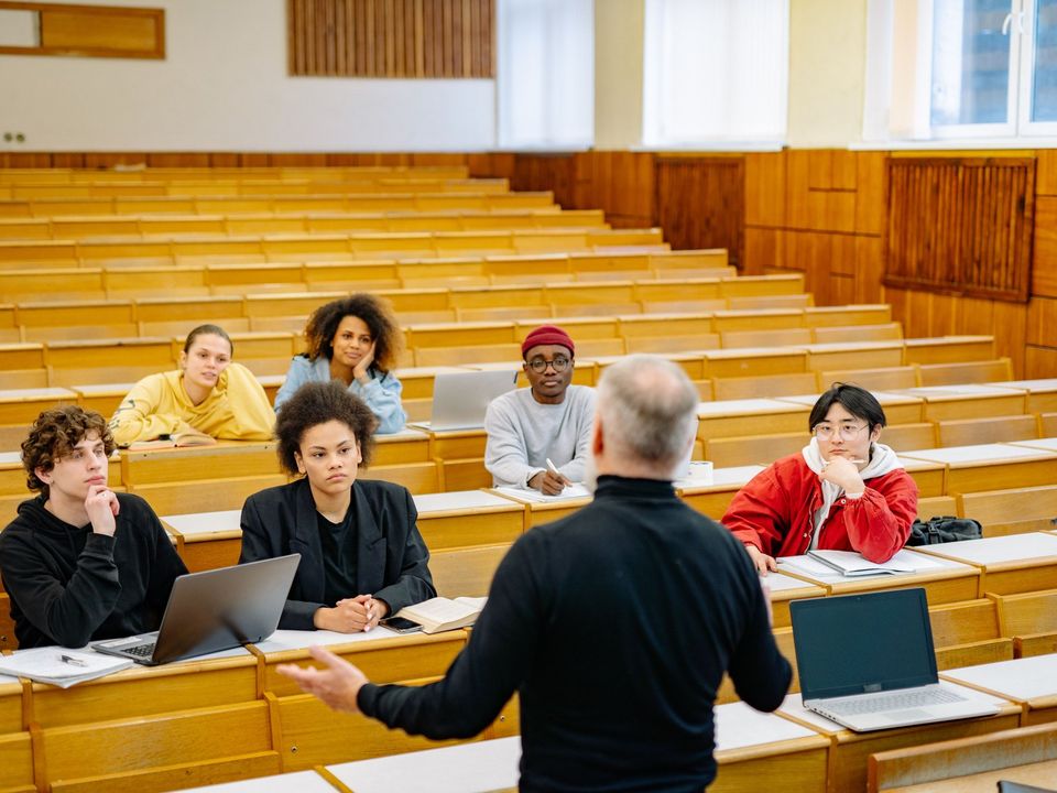 Students in a wooden lecture hall listening to a lecturer