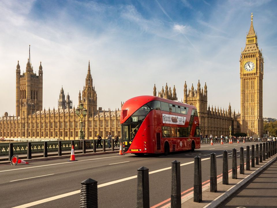 A red London bus passing the Houses of Parliament