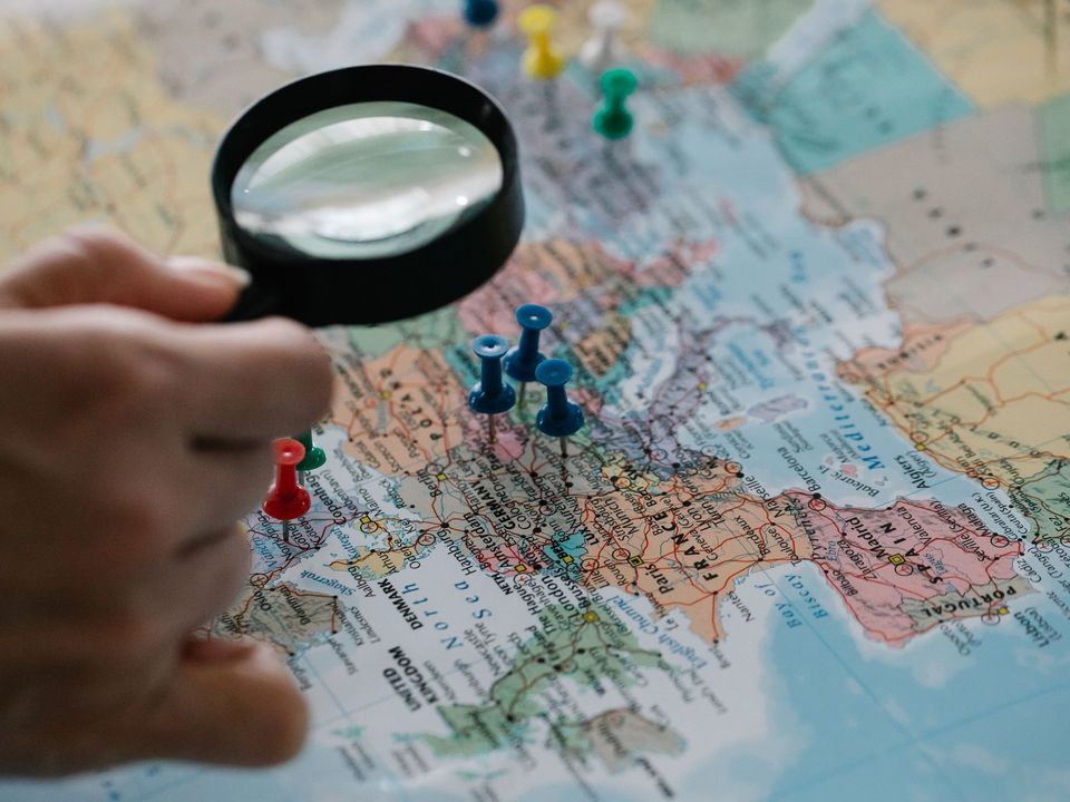 A magnifying glass over a world map marked with pins