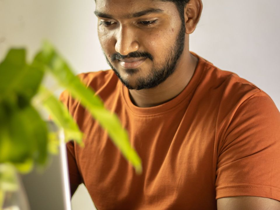 A young man working on a laptop at his desk